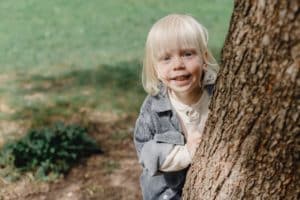 ילד מתחבא מאחורי עץ